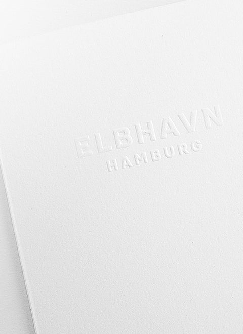 Geprägtes Logo von ELBHAVN, Hamburg, auf einem weißen Baumwoll-Papierkärtchen.