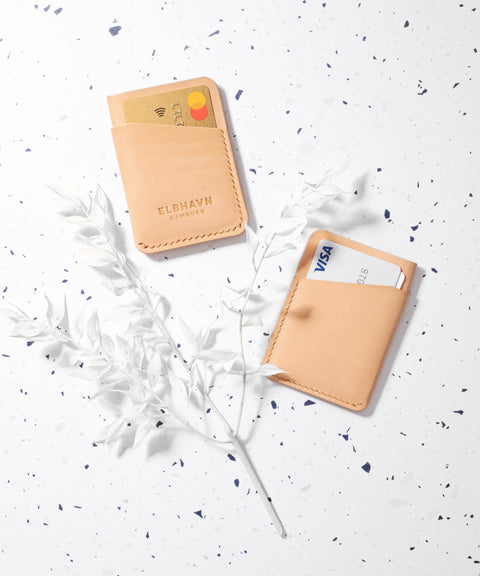 Mini-Kartenetui „Pocket Folio“ aus pflanzlich gegerbtem Leder mit Karten und Geldscheinen auf hellem Hintergrund.