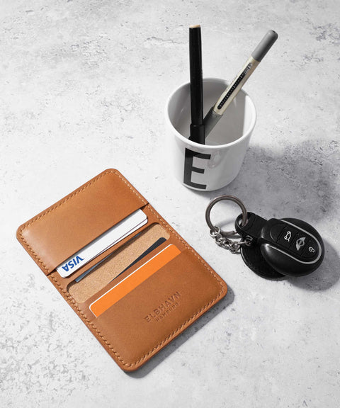 Kompaktes ELBHAVN Folio Wallet in Cognac mit Karten, Stift und Schlüssel auf einem Tisch. Draufsicht, Seitenansicht.