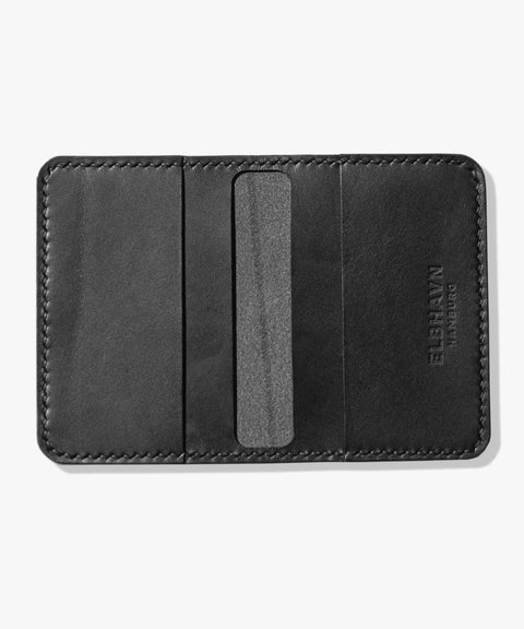 Kompaktes schwarzes Schwarzes Kartenetui "Folio" von ELBHAVN Hamburg aus Leder mit mehreren Fächern für Karten und Scheine, handgefertigt in Hamburg. Vorderseite, aufgeschlagen auf einem hellgrauen Hintergrund.