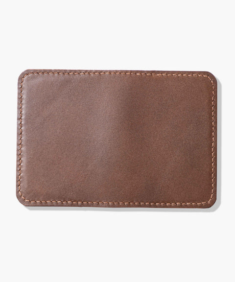 Kompaktes braunes Kartenetui "Folio" von ELBHAVN mit handgenähter Naht. Rückseite, aufgeschlagen auf einem hellgrauen Hintergrund.